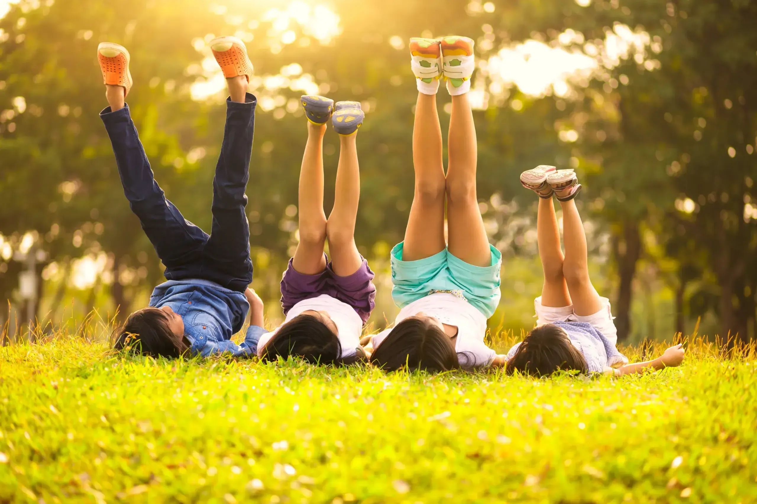 A group of people laying on top of a lush green field